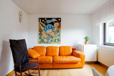 an orange couch in a living room with a chair at Green Point in Preserje