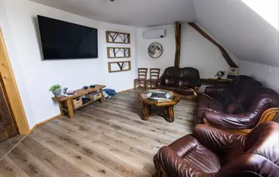 a living room with leather furniture and a flat screen tv at RANČ JUREŠ in Ljutomer