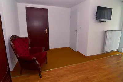 a room with a red chair and a flat screen tv at Emona Apartments in Ljubljana