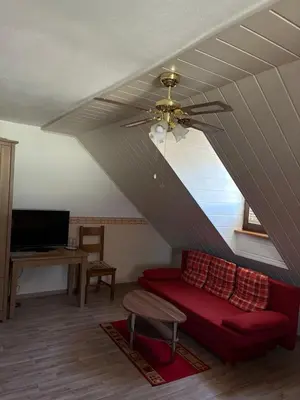 a living room with a red couch and a ceiling fan at Bed & Breakfast Pr'Sknet in Šenčur