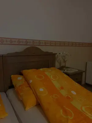 a bed with an orange blanket on top of it at Bed & Breakfast Pr'Sknet in Šenčur