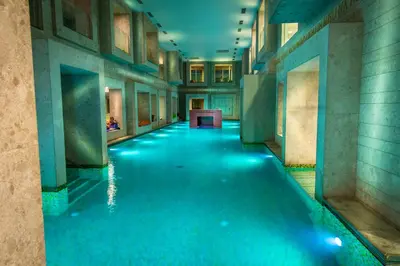 a long hallway with blue water in a building at Rimske Terme Resort - Hotel Zdraviliški dvor in Rimske Toplice