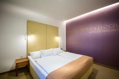 a bedroom with a large bed with a purple wall at Rimske Terme Resort - Hotel Zdraviliški dvor in Rimske Toplice