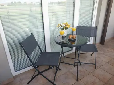 a table with chairs and a bowl of oranges on it at Red Rose Apartment in Moravske Toplice