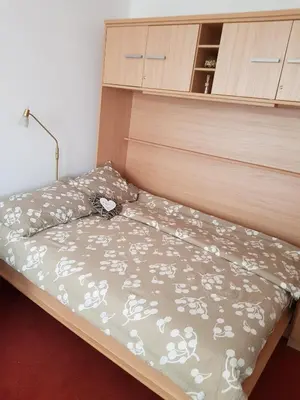 a bedroom with a bed with a wooden headboard at Red Rose Apartment in Moravske Toplice