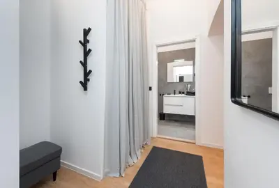 a living room with a black couch and a mirror at Apartments Rog in Ljubljana