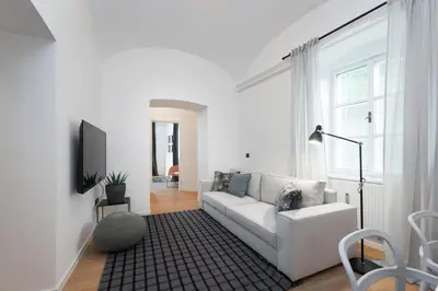 a white living room with a white couch and a tv at Apartments Rog in Ljubljana