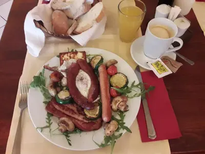 a plate of food with sausage and vegetables on a table at Hostel Piero in Ljubljana