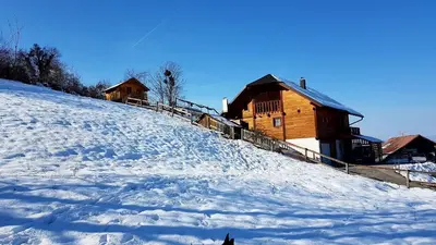 a snow covered hill with two wooden buildings at Gnezdo Vid-ik in Čatež ob Savi