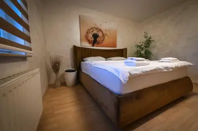 a bedroom with a large bed with white sheets at Apartments in Villa Olimp in Ljubljana