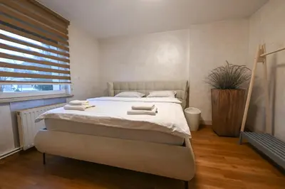 a bedroom with a bed with white sheets and a window at Apartments in Villa Olimp in Ljubljana