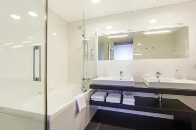 a bathroom with a tub and a sink and a mirror at HABAKUK Wellness & Event Hotel in Maribor