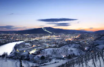 a city covered in snow with a mountain in the background at HABAKUK Wellness & Event Hotel in Maribor