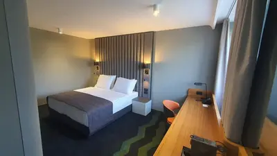 a small bedroom with a bed and a desk at HABAKUK Wellness & Event Hotel in Maribor
