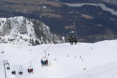 a group of people on a ski lift in the snow at Pristava Lepena Village in Lepena