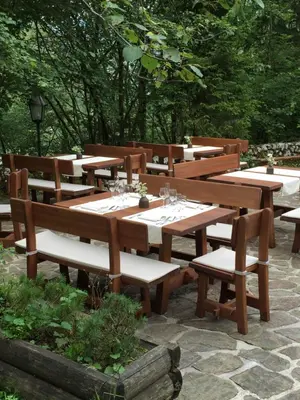 a group of wooden tables and benches with wine glasses at Pristava Lepena Village in Lepena