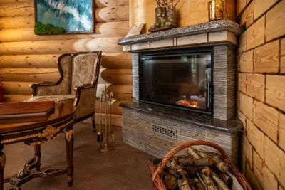 a living room with a fireplace in a log cabin at Pristava Lepena Village in Lepena