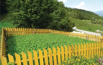 a yellow fence in front of a field of plants at 2 Bedroom Stunning Home In Luce in Luče