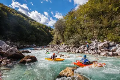 a group of people rafting down a river in kayaks at ApBovec in Bovec