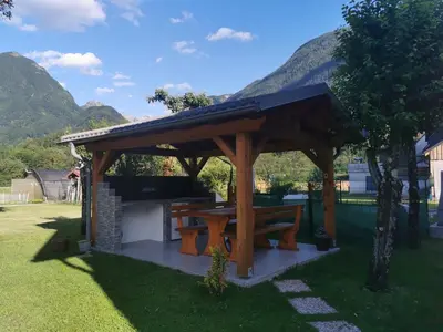 a wooden pavilion with a picnic table in a yard at Apartma Miko in Bovec