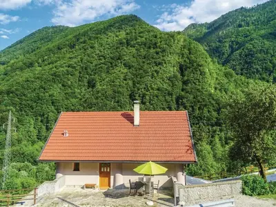a small house with a table and a yellow umbrella at Počitniška hiša Pri Kuštrču in Grahovo
