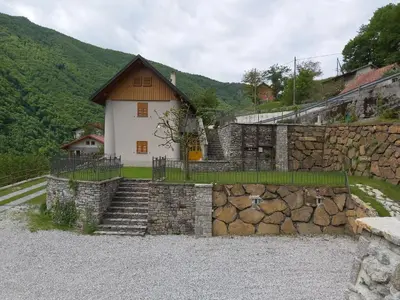 a house with a stone wall and stairs in front at Počitniška hiša Pri Kuštrču in Grahovo