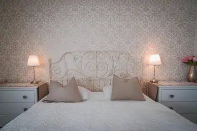a bedroom with a white bed with two lamps and flowers at Vacation House Vila Mia in Bled