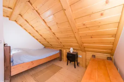 a room with a bed and a wooden ceiling at Koča na Planini in Planina pod Sumnikom