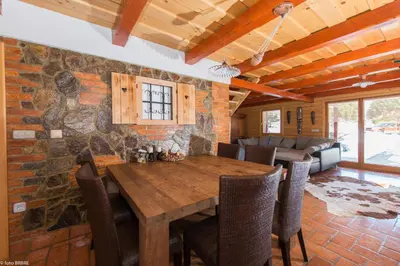 a dining room with a wooden table and a stone wall at Koča na Planini in Planina pod Sumnikom