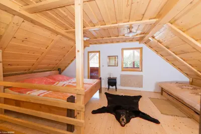 a bedroom with two bunk beds in a log cabin at Koča na Planini in Planina pod Sumnikom
