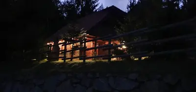 a log cabin at night with a fence at Koča na Planini in Planina pod Sumnikom