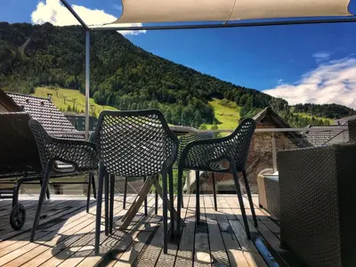 three chairs and an umbrella on a deck with a mountain at House Neza in Kranjska Gora