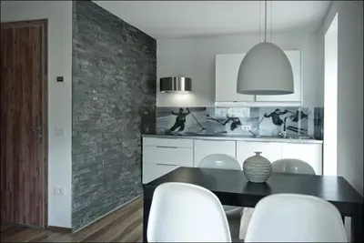 a kitchen with a black table and white chairs at House Neza in Kranjska Gora