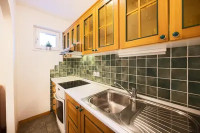 a kitchen with a stainless steel sink and wooden cabinets at Apartments Baki Kranjska Gora in Kranjska Gora