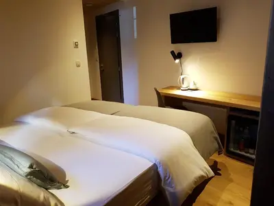 a hotel room with two beds and a desk with a television at Hotel Vandot in Kranjska Gora