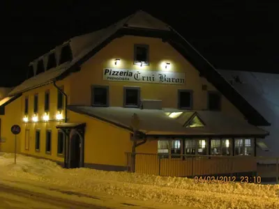 a building with a sign on it in the snow at Črni Baron Pension Black Baron in Maribor