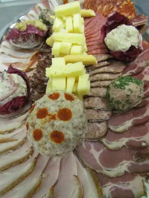 a plate of food with meat cheese and other foods at Črni Baron Pension Black Baron in Maribor