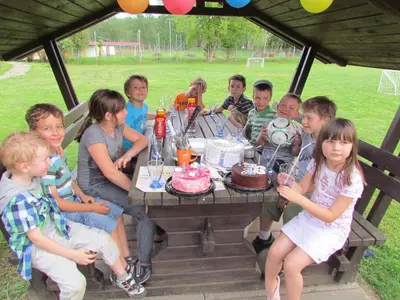 a group of children sitting around a table with cakes at Črni Baron Pension Black Baron in Maribor