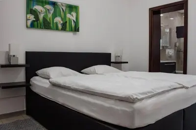 a bedroom with a large bed with white sheets at Črni Baron Pension Black Baron in Maribor