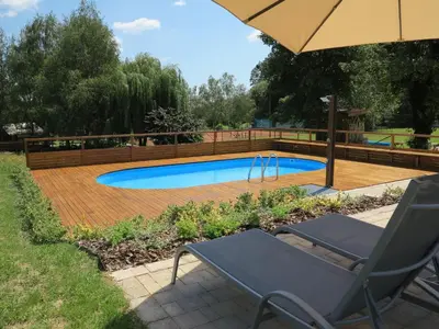 a swimming pool with a chair and an umbrella at Naturasort Holiday Houses in Pesnica pri Mariboru