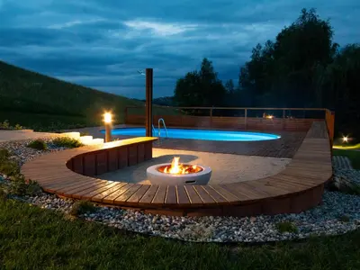 a patio with a fire pit and a pool at night at Naturasort Holiday Houses in Pesnica pri Mariboru