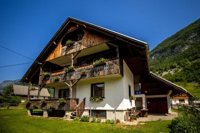 a house with a gambrel roof with a balcony at Apartment and room Mateja Kovačič in Bohinj