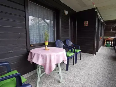 a table and chairs on the back porch of a house at Apartment and room Mateja Kovačič in Bohinj