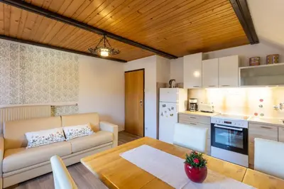 a kitchen and living room with a couch and a table at Apartment and room Mateja Kovačič in Bohinj