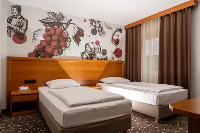 two beds in a hotel room with a mural on the wall at Hotel Piramida in Maribor