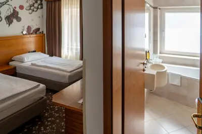 a hotel room with two beds and a bathroom at Hotel Piramida in Maribor