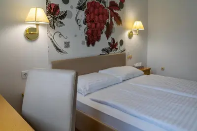 a bedroom with a bed and two lights on the wall at Hotel Piramida in Maribor