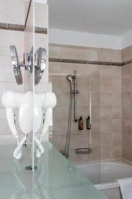 a bathroom with a shower and a toilet and a tub at Hotel Piramida in Maribor