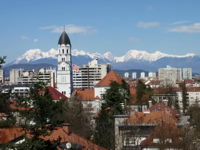 a city with a clock tower with mountains in the background at Saint Ignatius Retreat House in Ljubljana