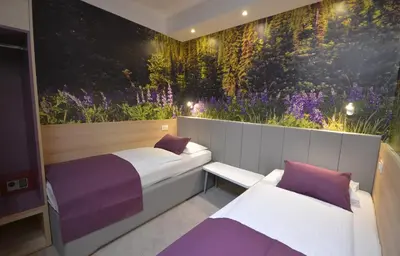 two beds in a room with a mural of flowers at Hotel Emonec in Ljubljana